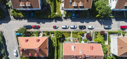 Aire view of a neibourghood with green gardens and cars parked on the Street.