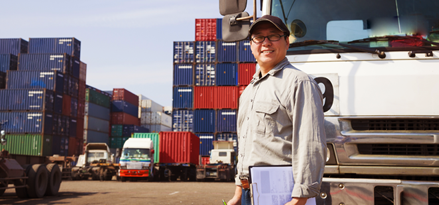 Truck driver smiling standing in front of his truck.