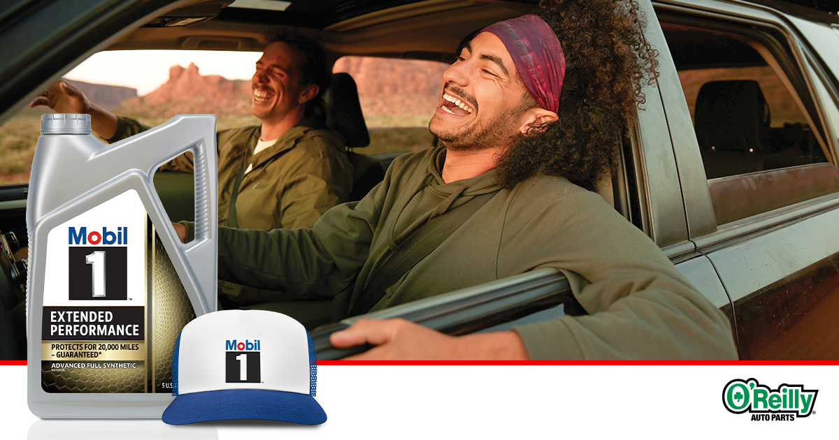 A stylish Mobil 1™ trucker hat set against a road-ready backdrop. We see two guys in a car having fun on a road trip.