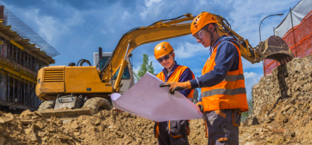 Two construction workers on site looking at a blueprint