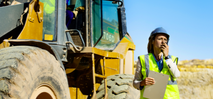 construction worker standing next to equipment using radio