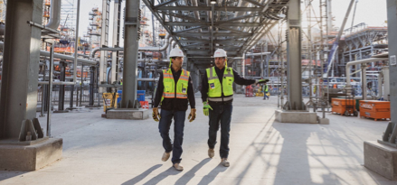 workers walking through outdoor plant site wearing hardhats