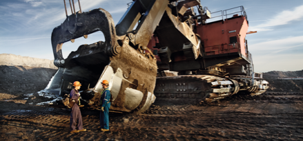 Mining workers talking on job site in front of digging equipment