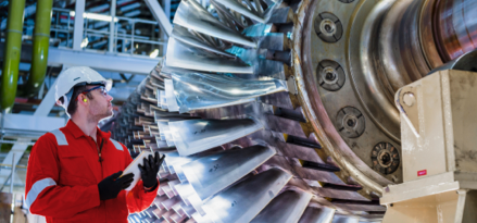 worker wearing hardhat standing next to turbine