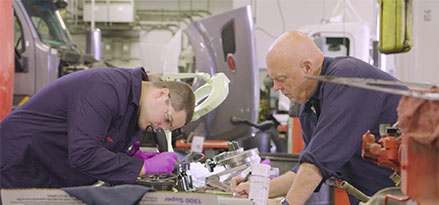 Two technicians working on truck engine together