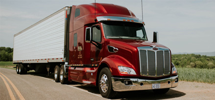 Front side view of truck with red cab on highway