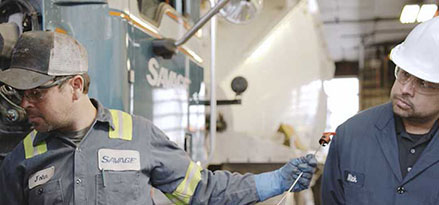 Technician working on truck mainteannce while a second technician observes.