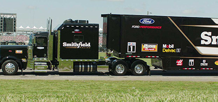 Sideview of large black truck featuring Smithfield company name parked outside event