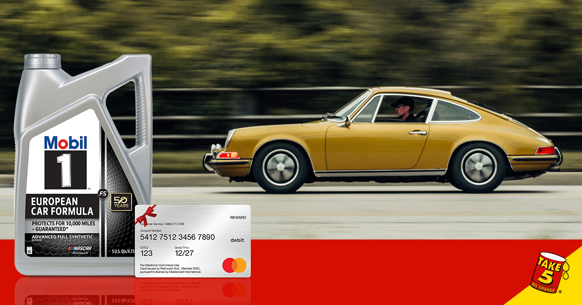 Side profile of a golden-yellow Porsche driving down a tree-lined road as the background blurs. A bottle of Mobil 1 European Formula and a gift card sit in the foreground