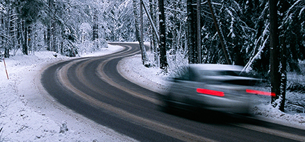 Mobil 1™ oil in car driving in cold weather with snow on ground and trees